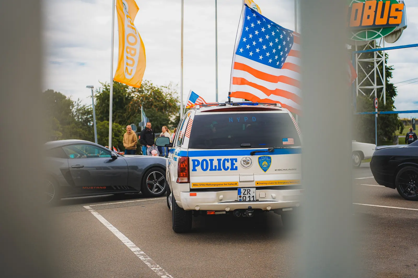 Polizei-Geländewagen im New-York-Look mit US-Flagge, durch einen Zaun gesehen