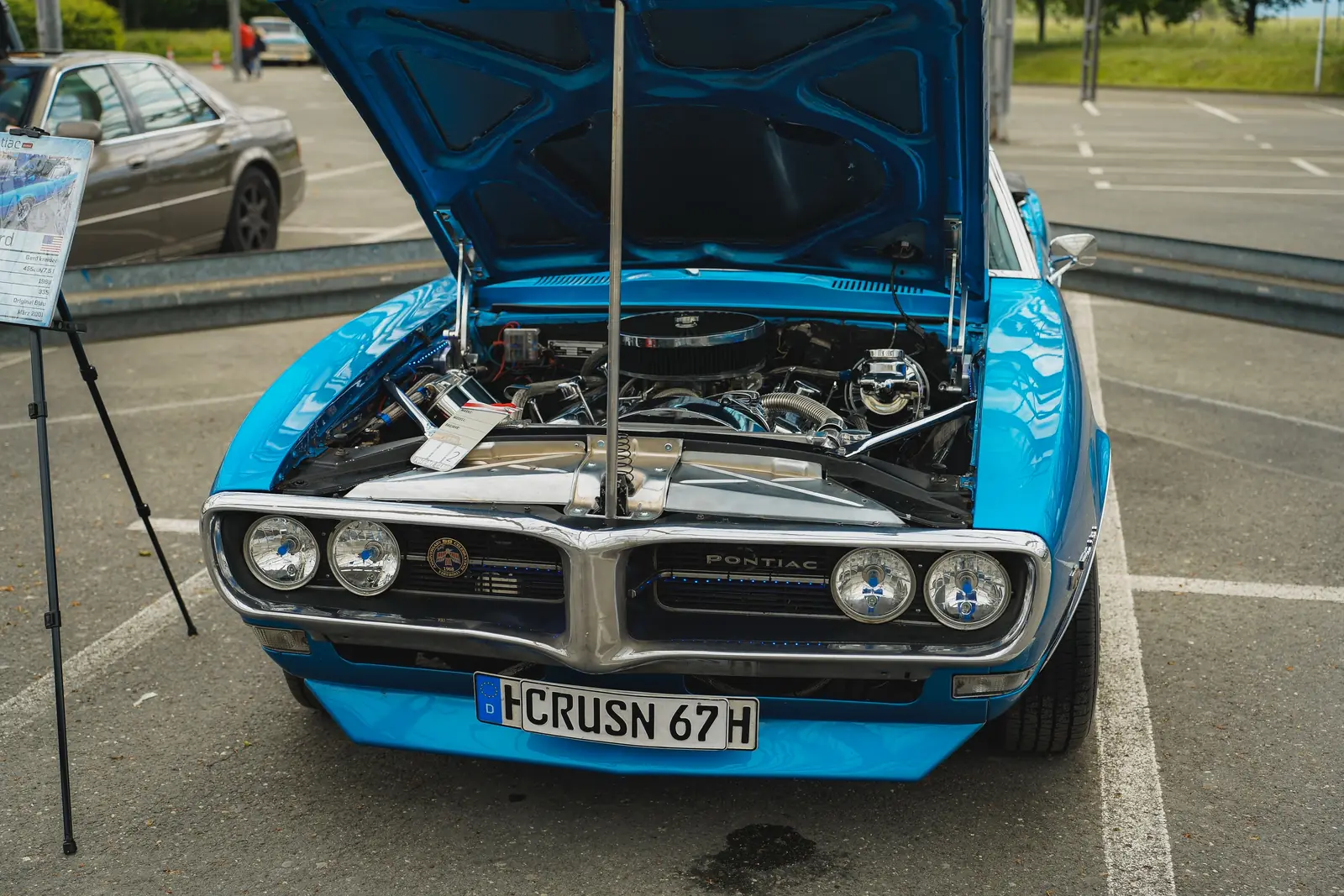 Blauer Pontiac Firebird mit offener Motorhaube und Infotafel