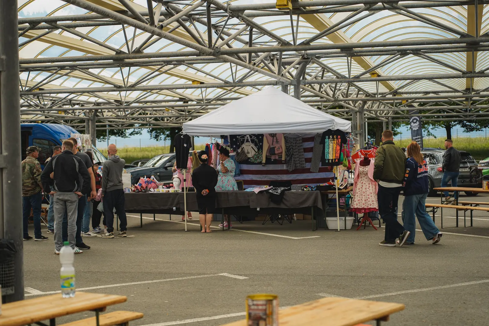 Stand mit US-Flaggen, Kleidern und Taschen, davor Besucher