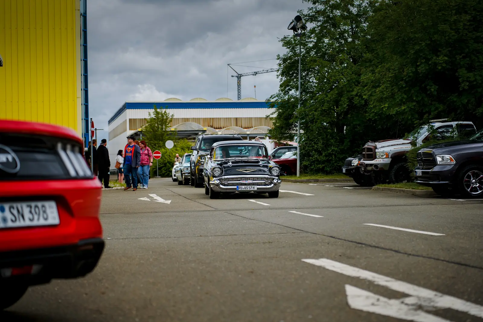 Schwarzer Chevrolet Bel Air rollt auf den Platz, vorn das Heck eines roten Mustangs