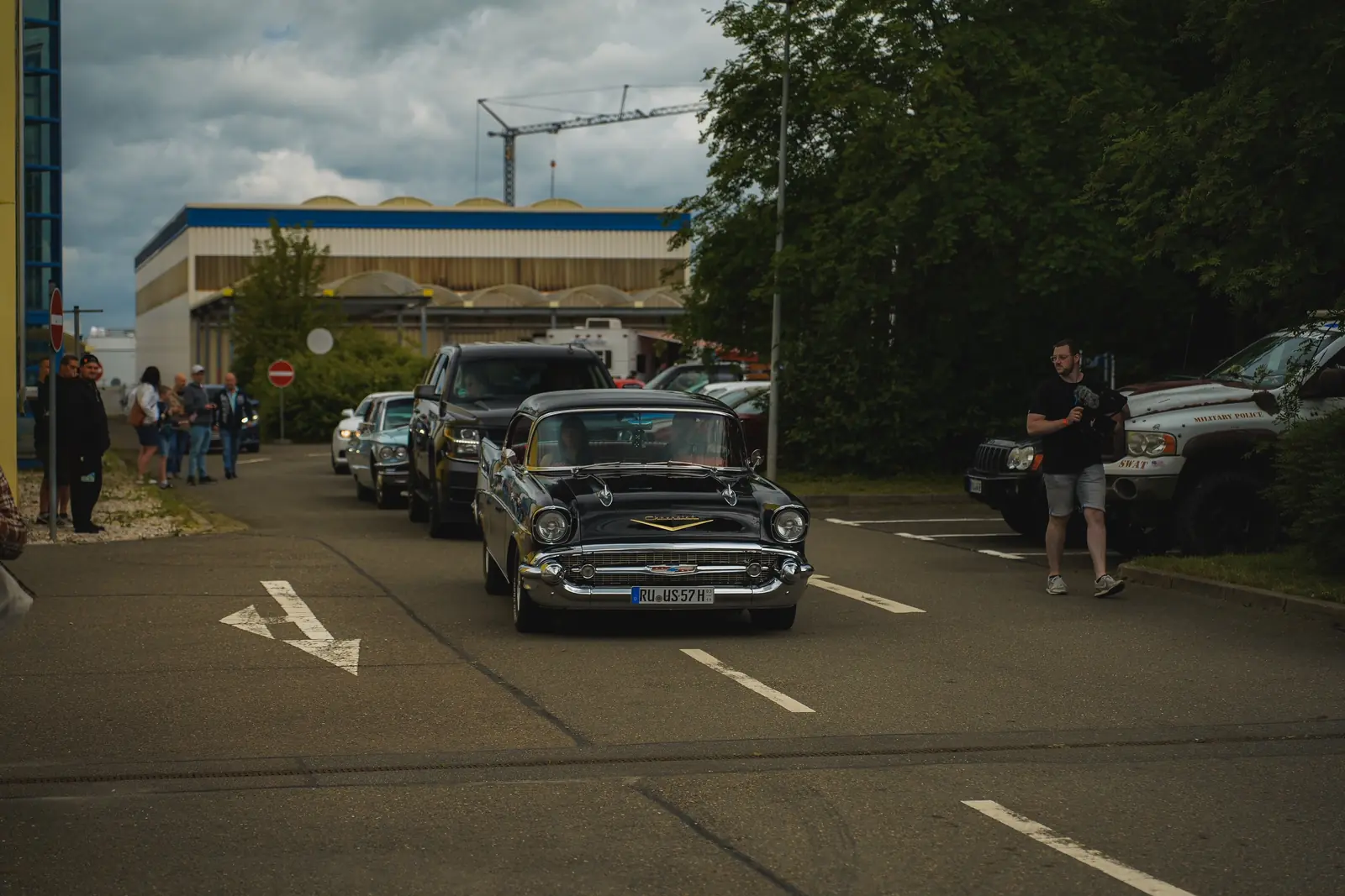 Schwarzer Chevrolet Bel Air in der Zufahrt, daneben Pick-ups