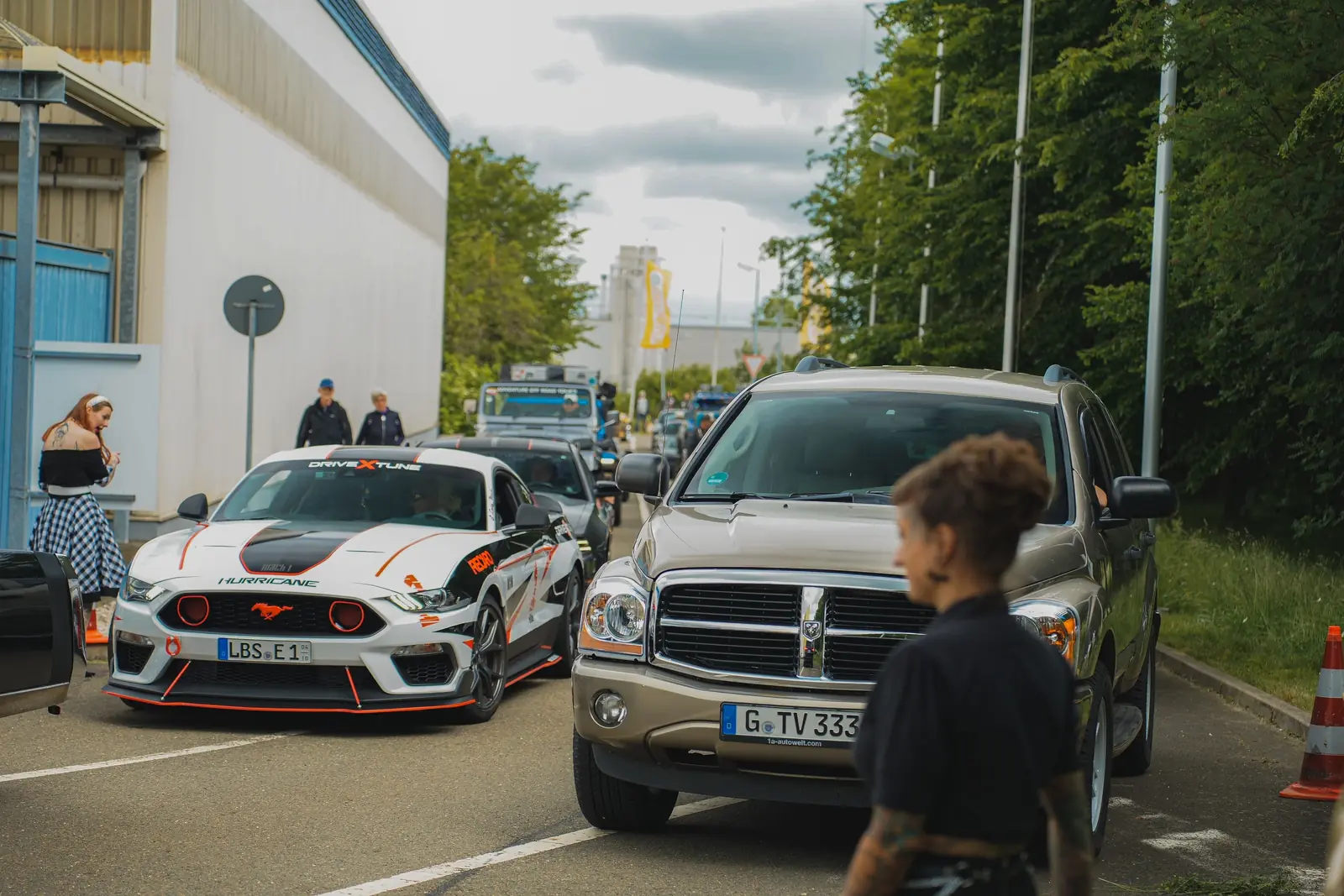 Weiß-roter Mustang und grauer Dodge Durango an der Einfahrt