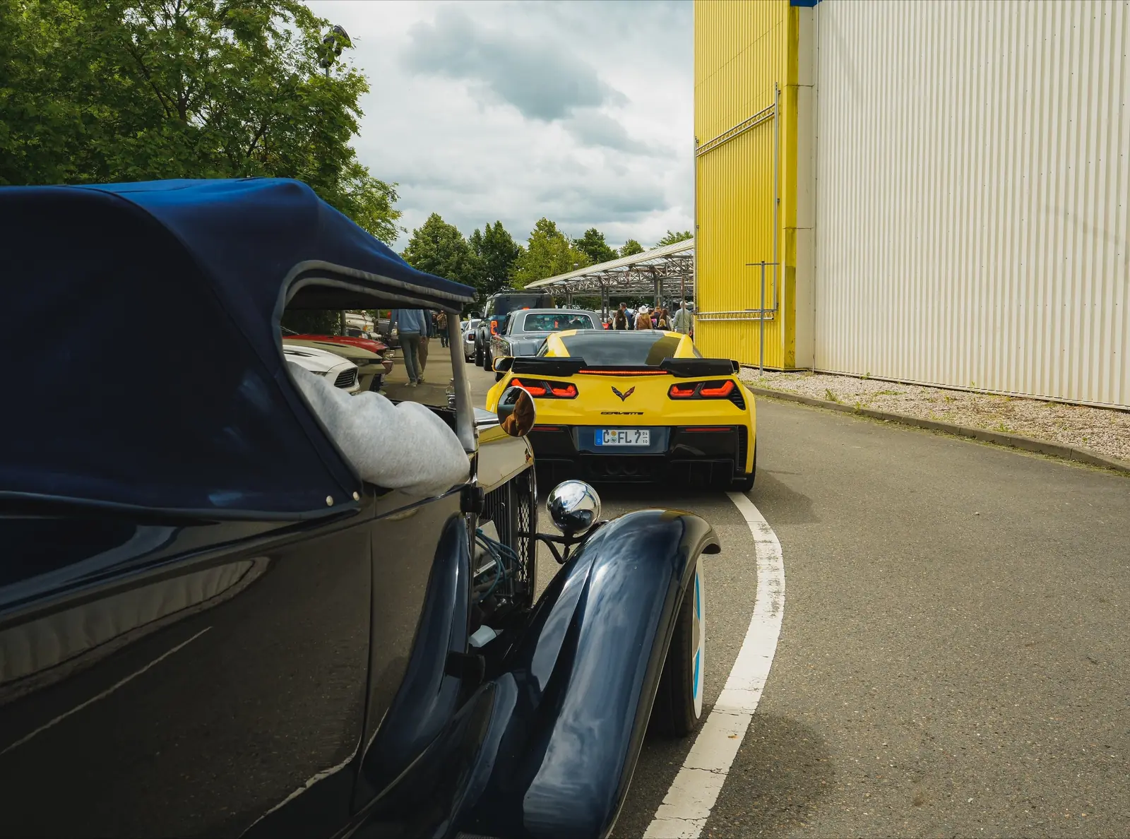Schwarzer Hot Rod mit Verdeck, dahinter eine gelbe Corvette