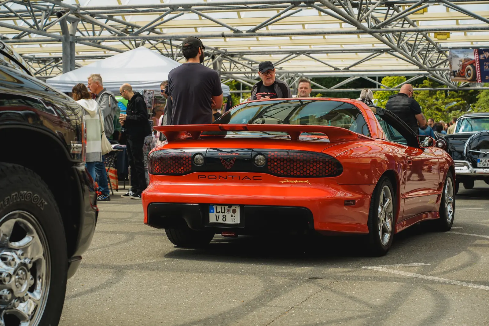 Roter Pontiac Firebird von hinten zwischen Besuchern