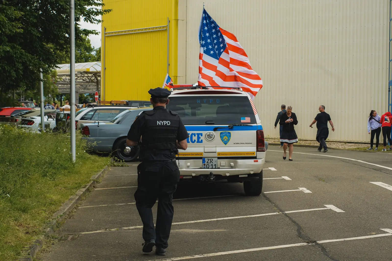 Mann in NYPD-Uniform läuft zum Polizei-Geländewagen mit großer US-Flagge