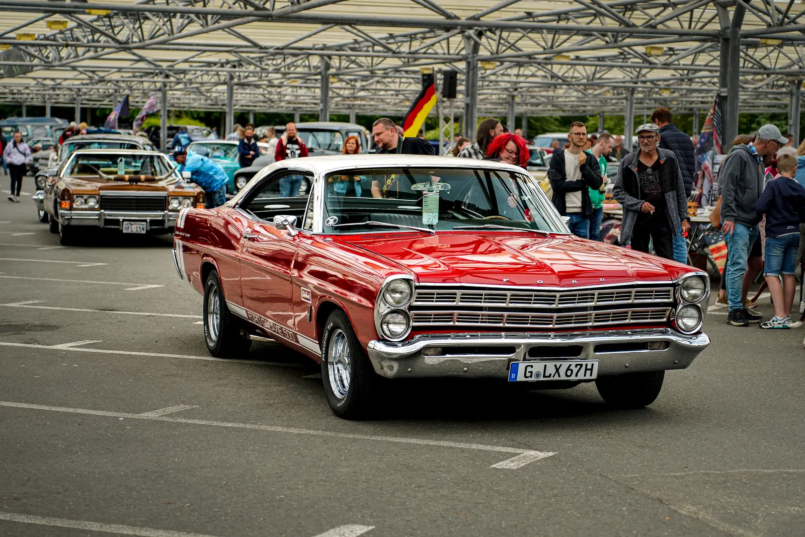Roter Ford Galaxie mit weißem Dach zwischen Besuchern unter dem Glasdach