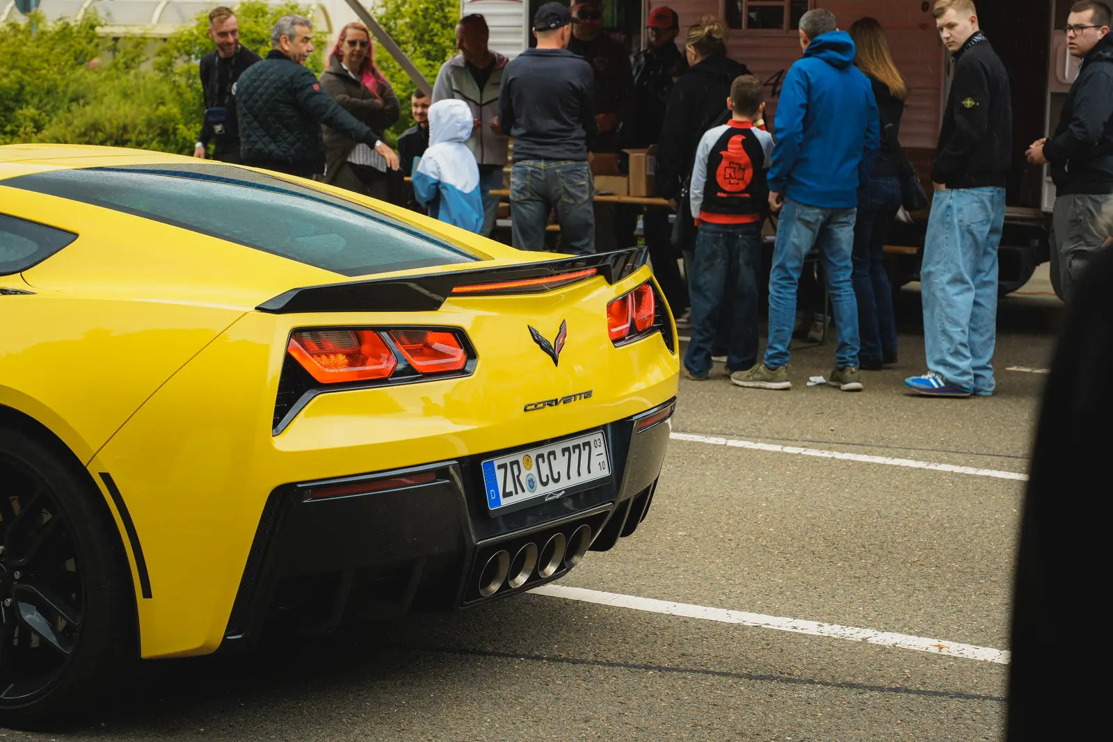 Heck einer gelben Corvette vor Besuchern am Imbiss