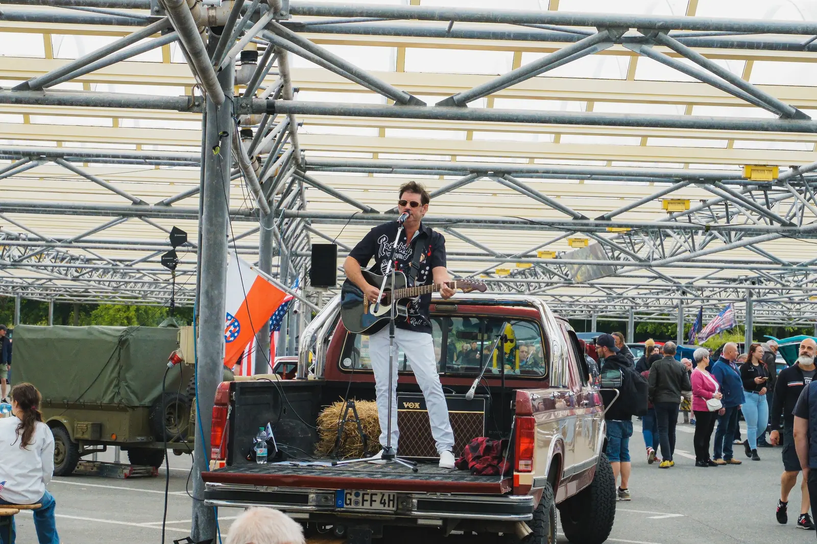 Sänger mit Gitarre auf der Ladefläche eines Pick-ups unter dem Glasdach