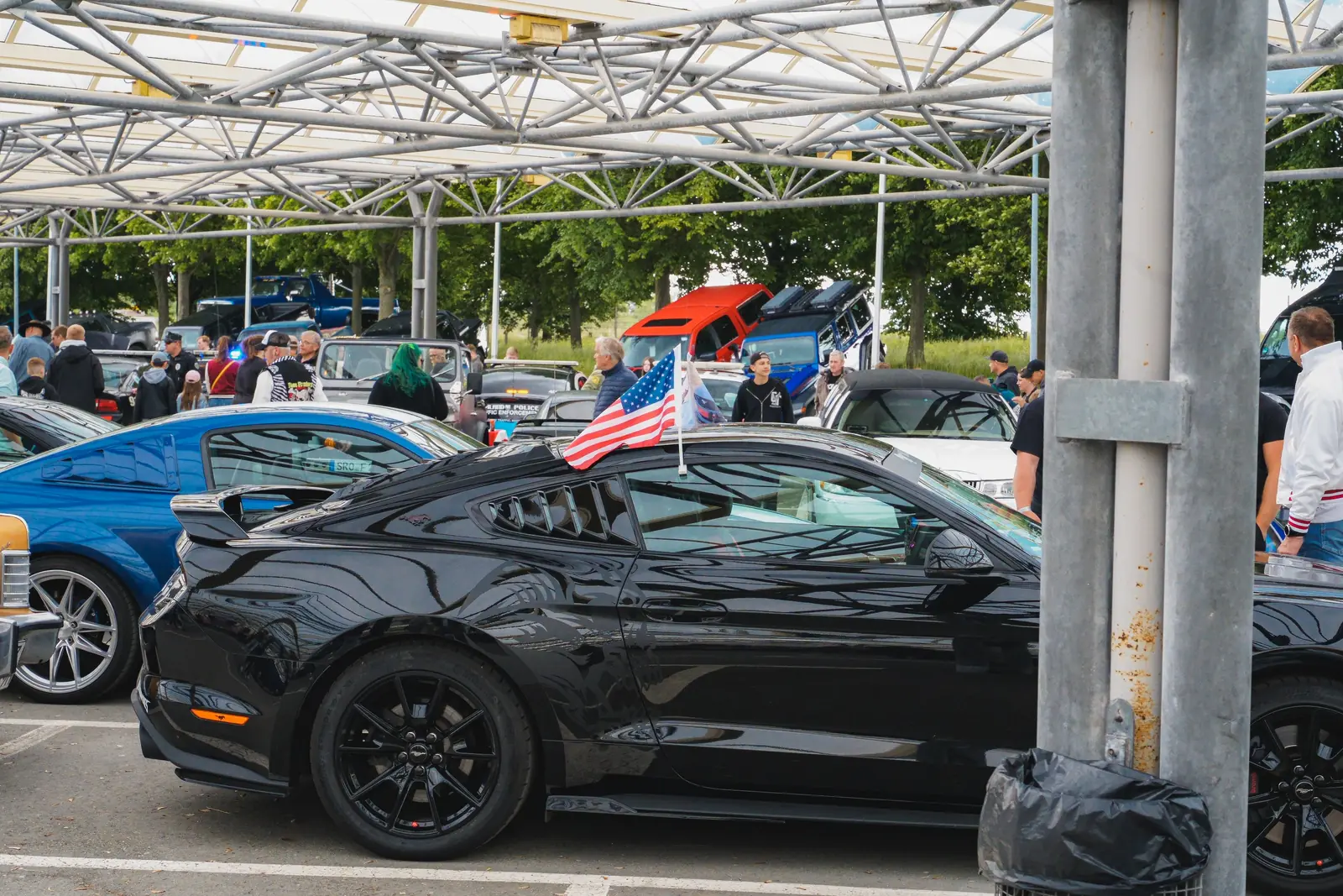 Schwarzer Mustang von der Seite mit US-Fähnchen am Fenster