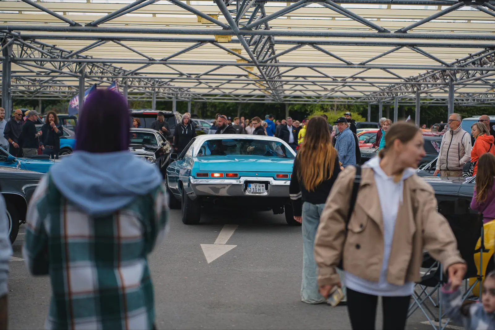 Besucher zwischen den Reihen, hinten ein hellblauer Chevrolet