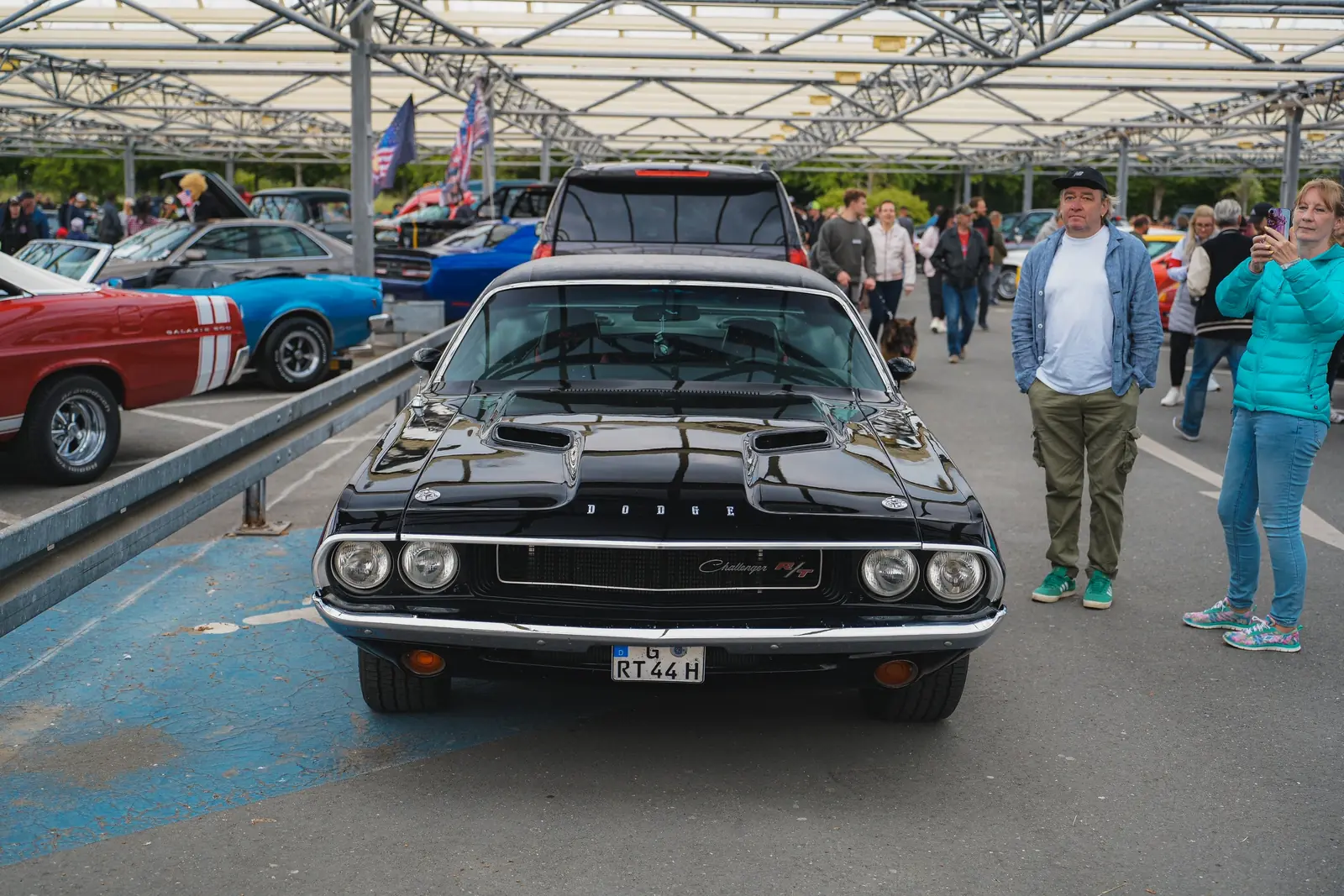 Schwarzer Dodge Challenger aus den Siebzigern zwischen Besuchern