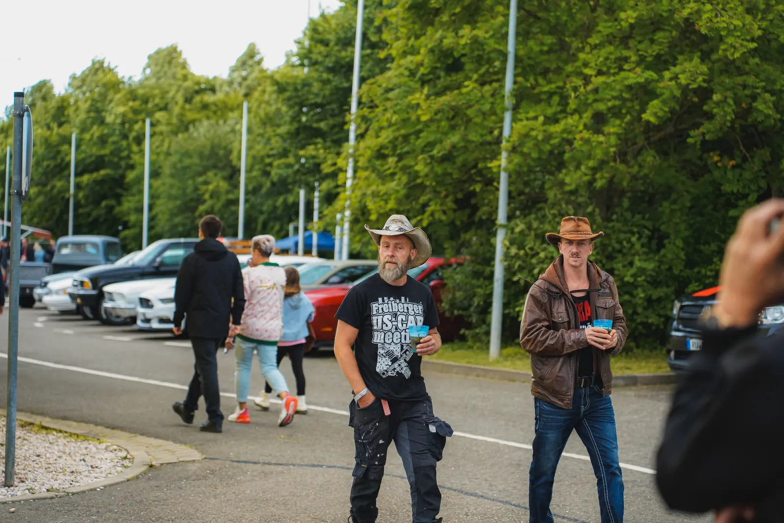 Zwei Besucher mit Cowboyhut kommen über den Platz