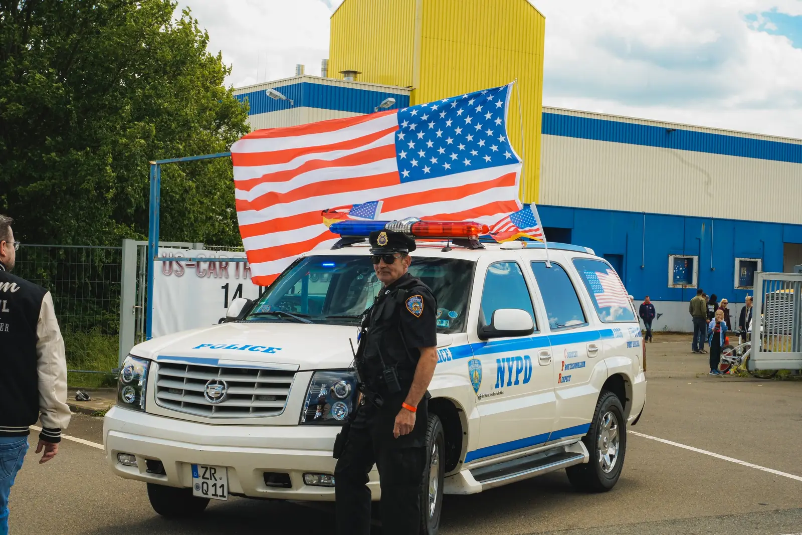 Mann in NYPD-Uniform vor dem Polizei-Geländewagen mit US-Flagge