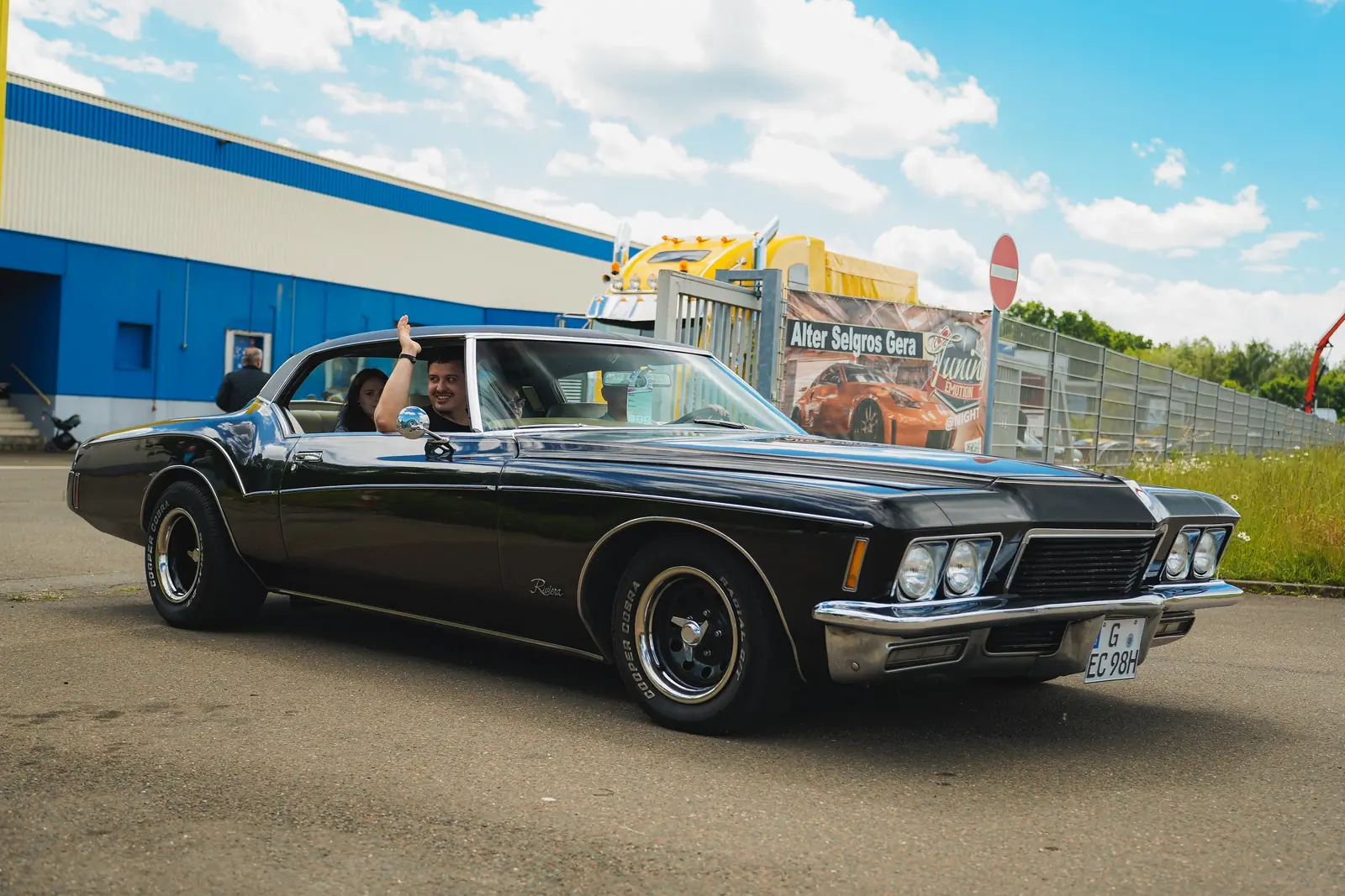 Schwarzer Buick Riviera aus den Siebzigern, der Fahrer winkt