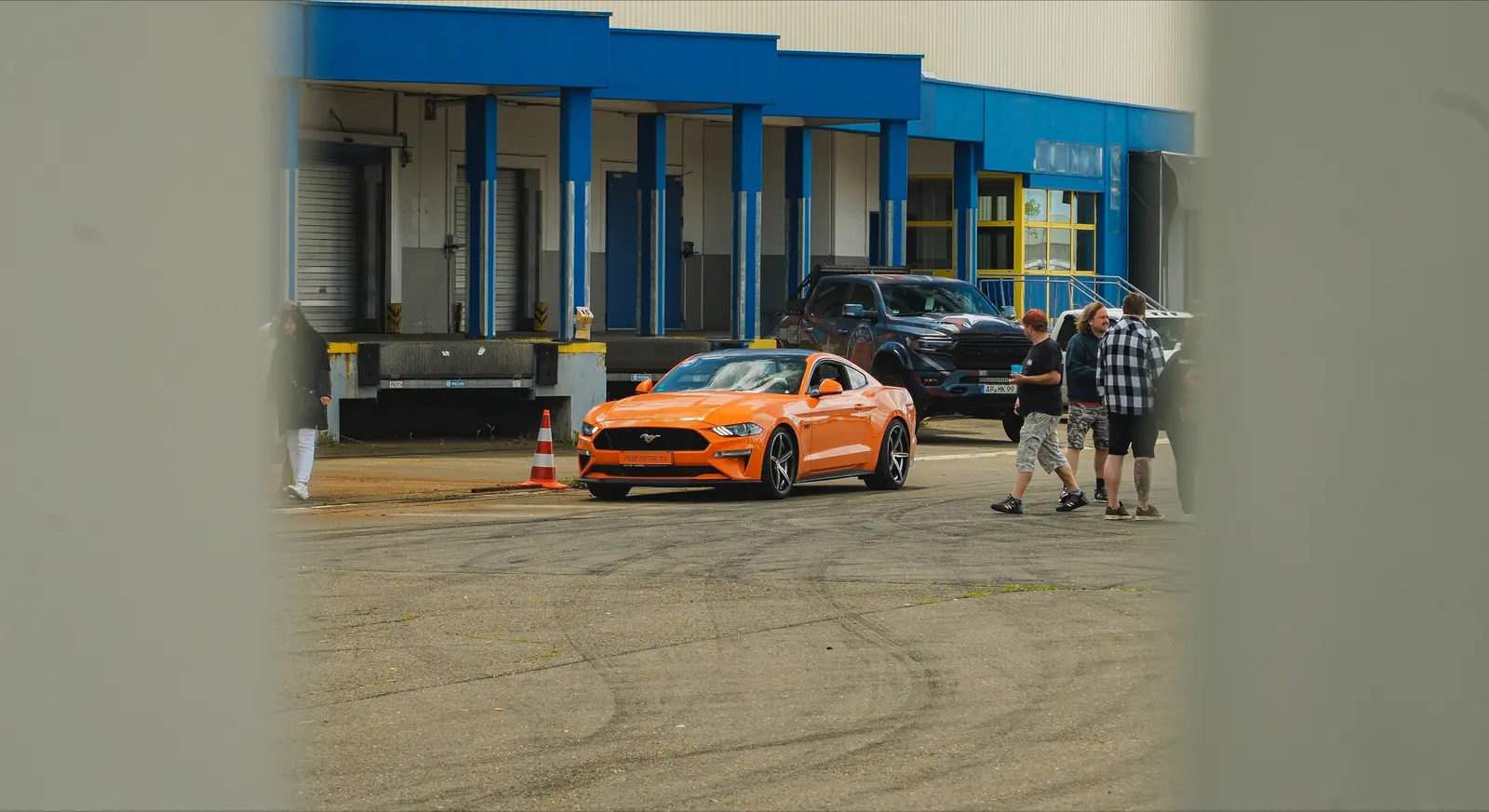 Oranger Mustang auf dem Platz, durch eine Lücke gesehen