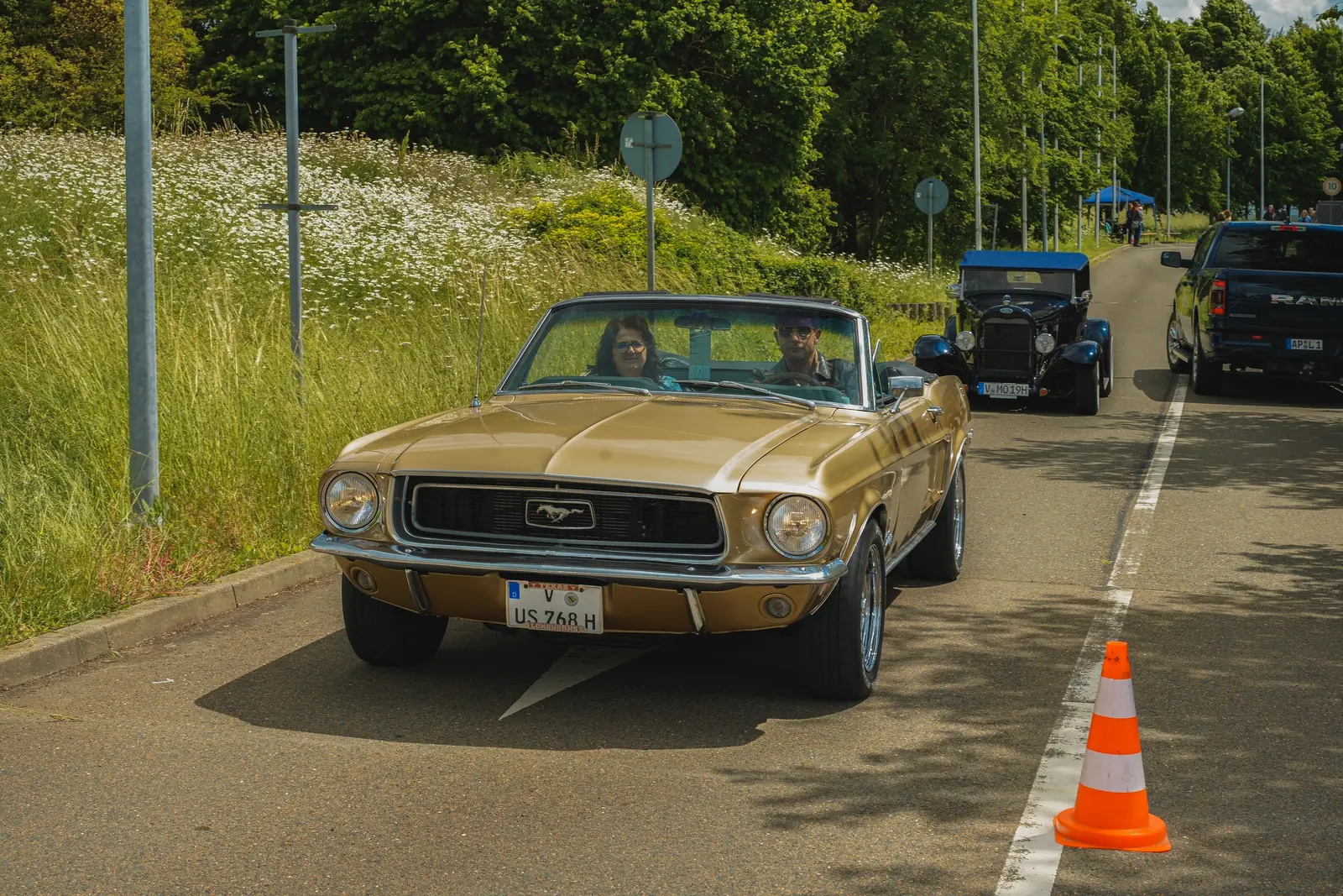 Goldenes Mustang-Cabrio aus den Sechzigern rollt die Zufahrt entlang