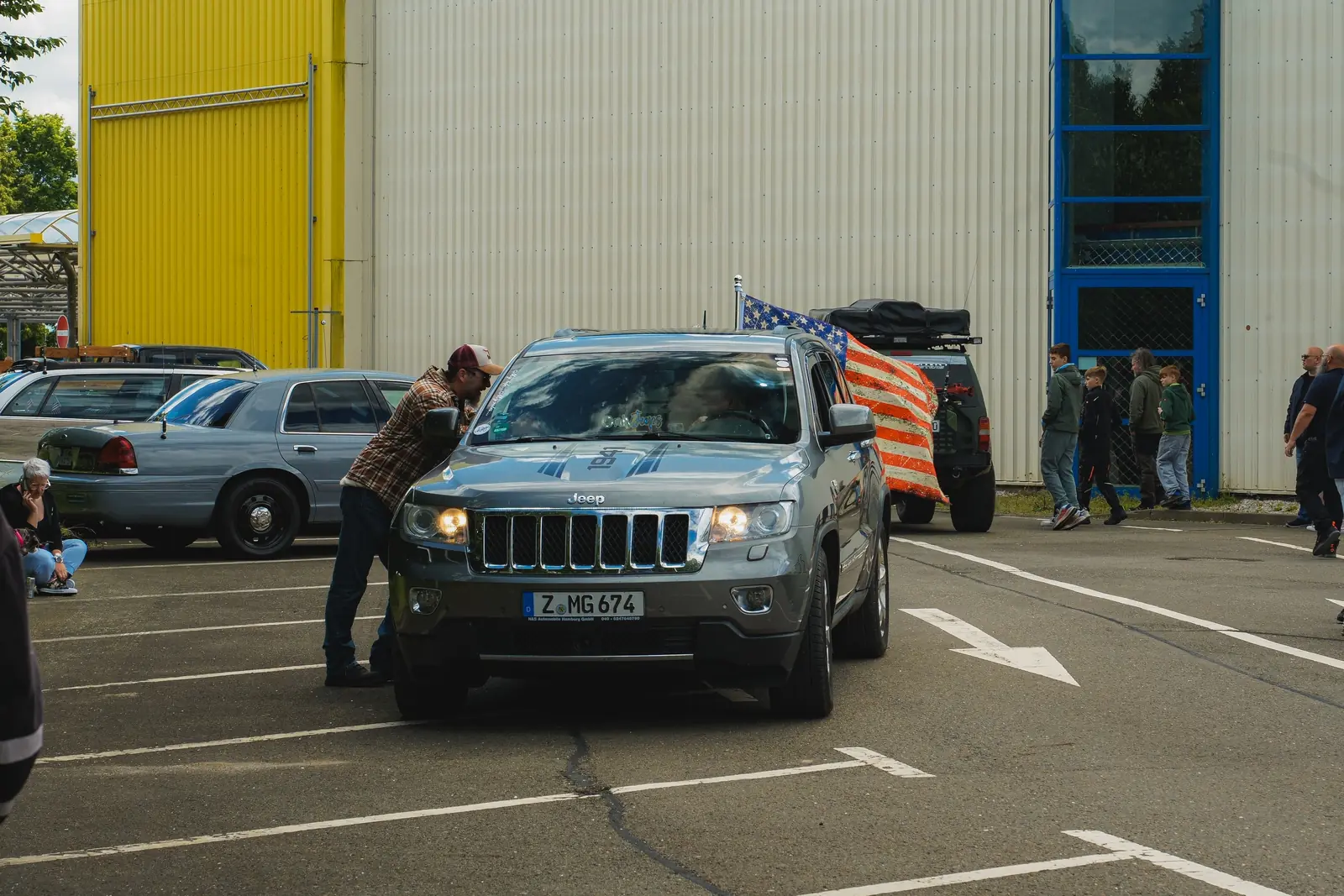 Grauer Jeep Grand Cherokee, dahinter eine US-Flagge