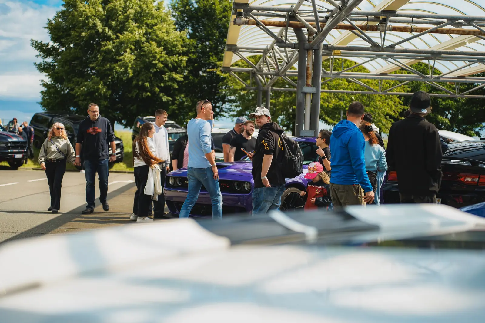 Besucher um einen violetten Challenger unter dem Glasdach