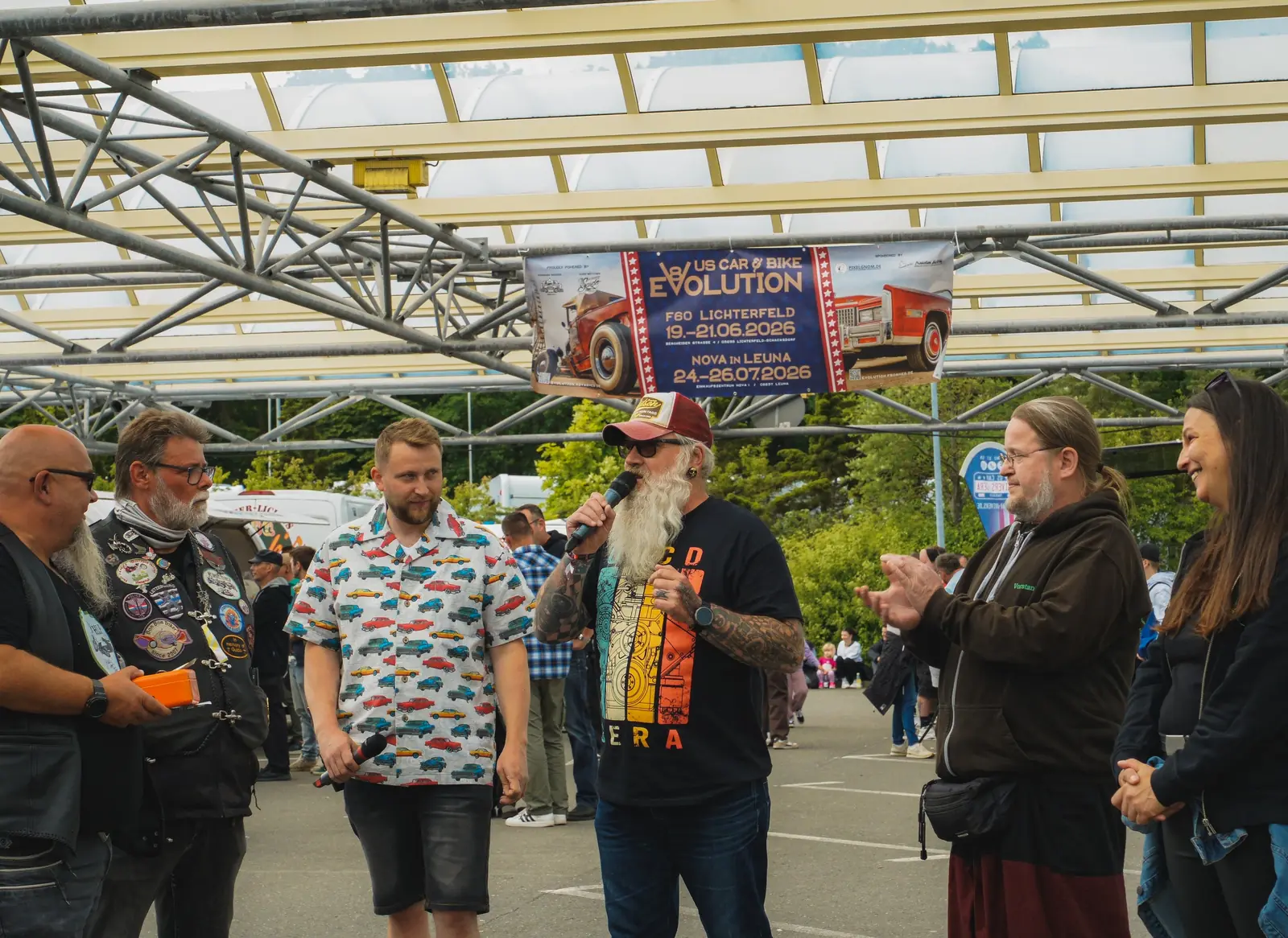 Moderatoren und Gäste in Kutten lachen vor dem Publikum