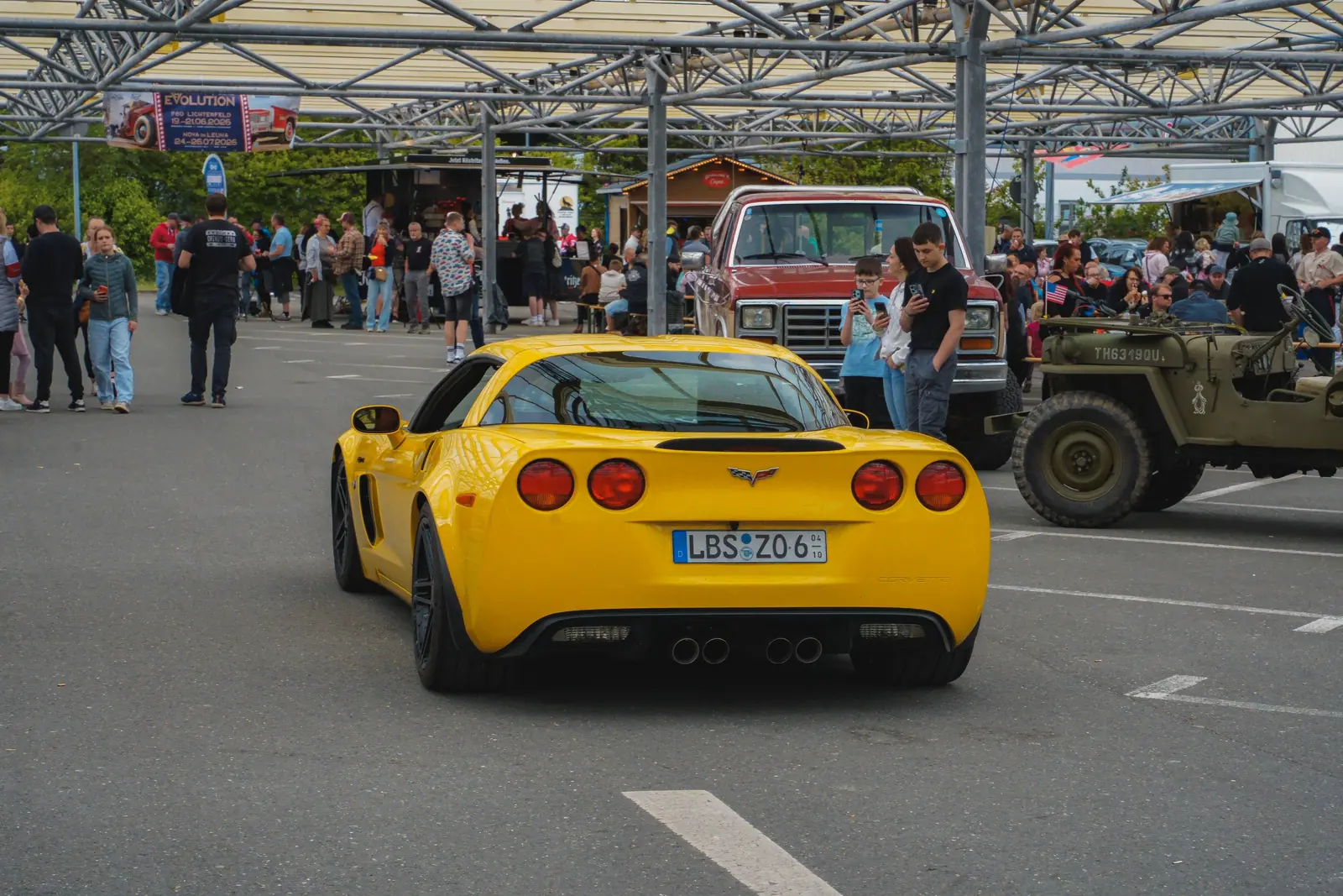 Gelbe Corvette von hinten vor vollem Platz