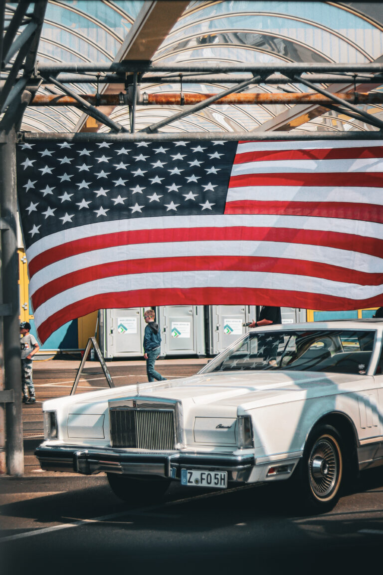 Weißer Lincoln vor einer großen US-Flagge