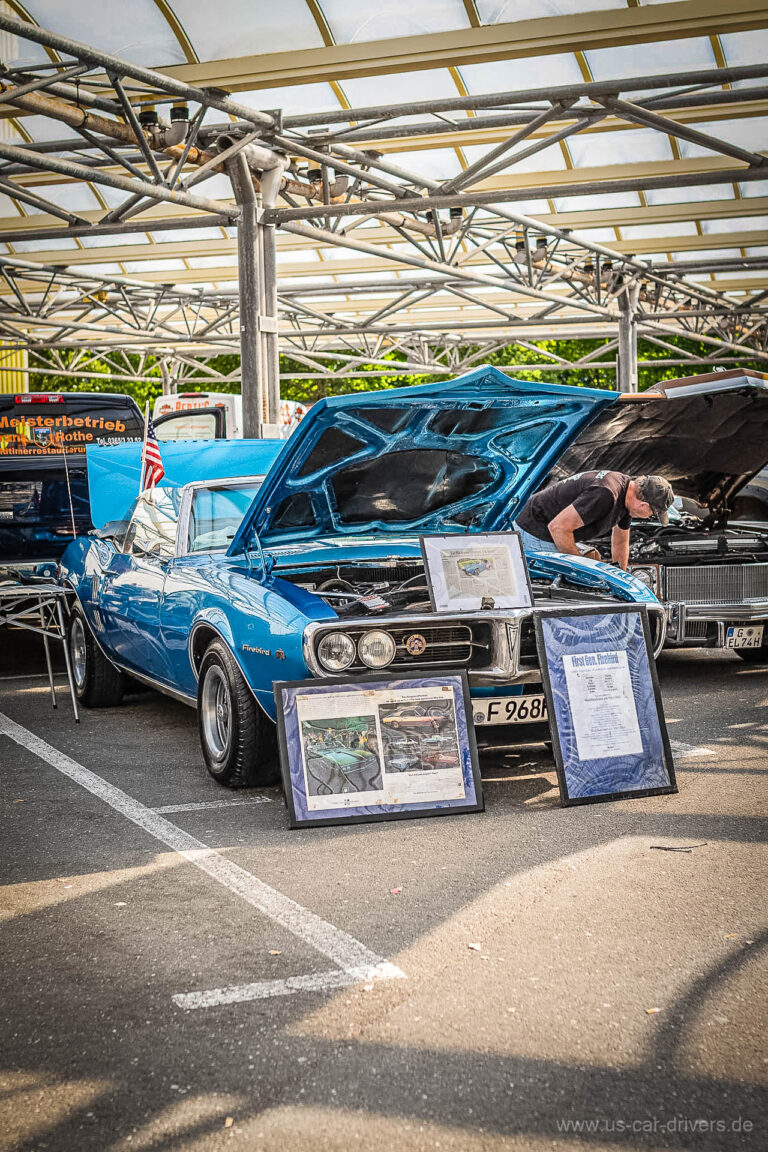 Blauer Muscle Car mit offener Motorhaube und Infotafeln