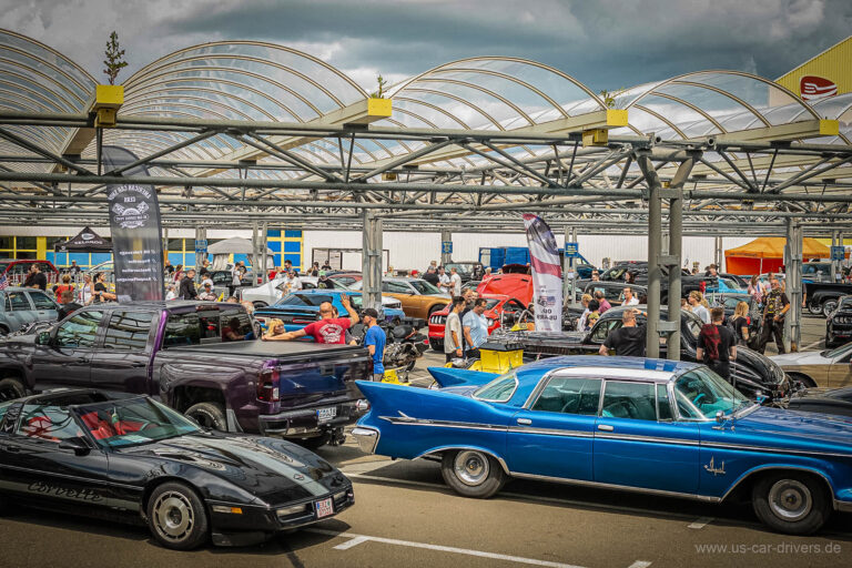 Schwarze Corvette und blauer Oldtimer unter dem Hallendach