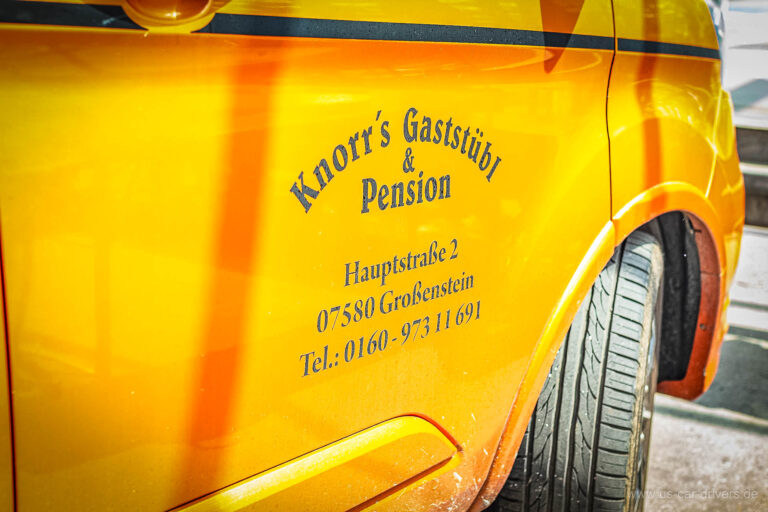 Gelbe Seitenwand eines Wagens mit Schriftzug eines Gasthauses