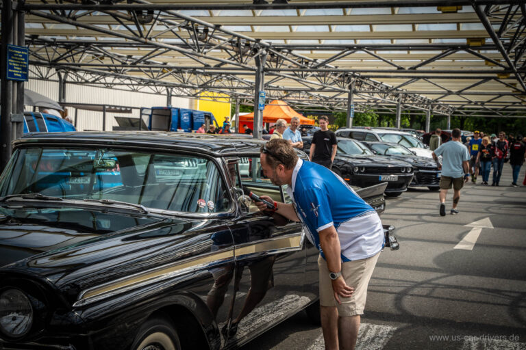 Besucher beugt sich in einen schwarzen Ford Thunderbird