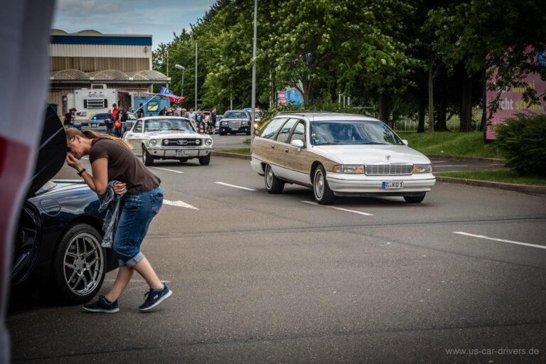 Besucher poliert einen Wagen, ein Kombi rollt vorbei