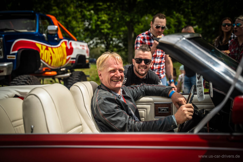 Lachende Besucher in einem roten Cabrio, Treffen 2024