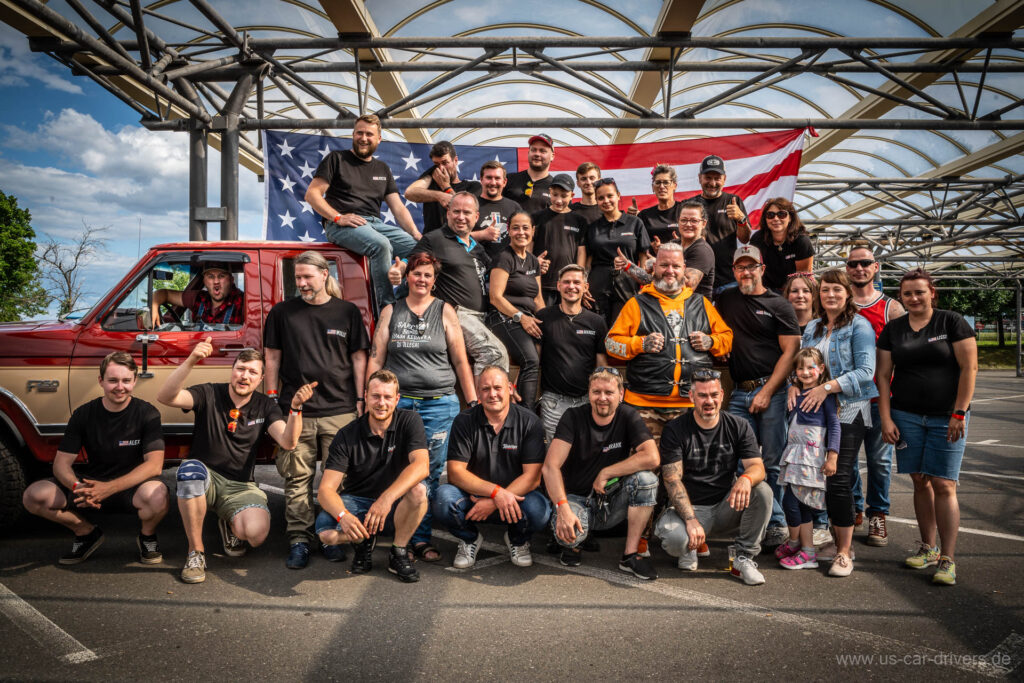 Gruppenfoto der US Car Drivers Gera vor einer großen US-Flagge