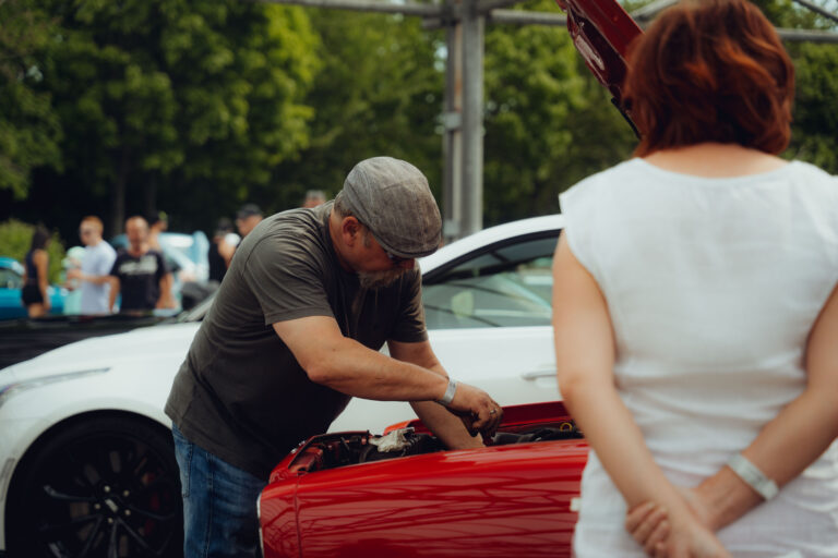 Besucher schaut sich den Motor eines roten Wagens an