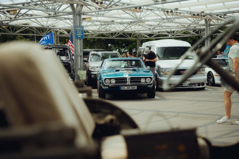 Blauer Muscle Car zwischen Besuchern unter dem Hallendach
