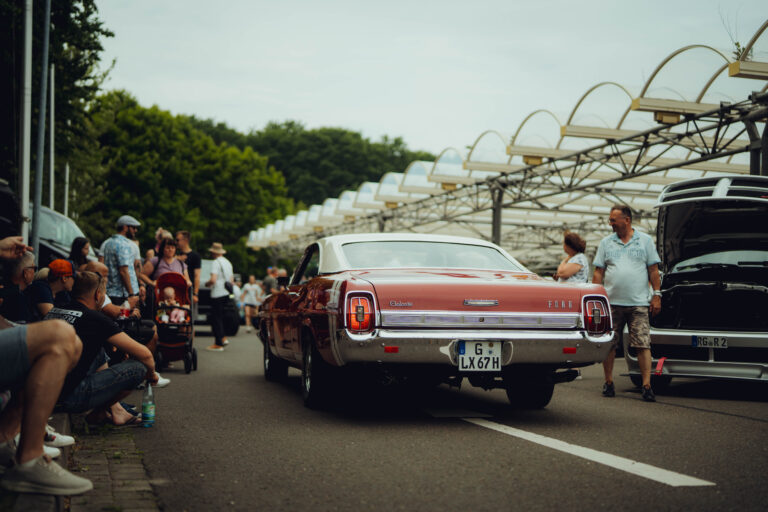 Roter Ford Galaxie von hinten zwischen Besuchern