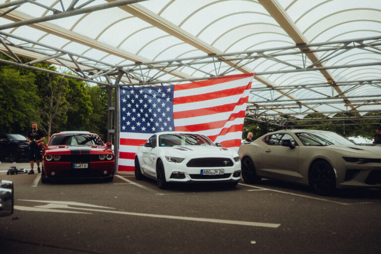 Große US-Flagge über einer Reihe Mustangs und Camaros