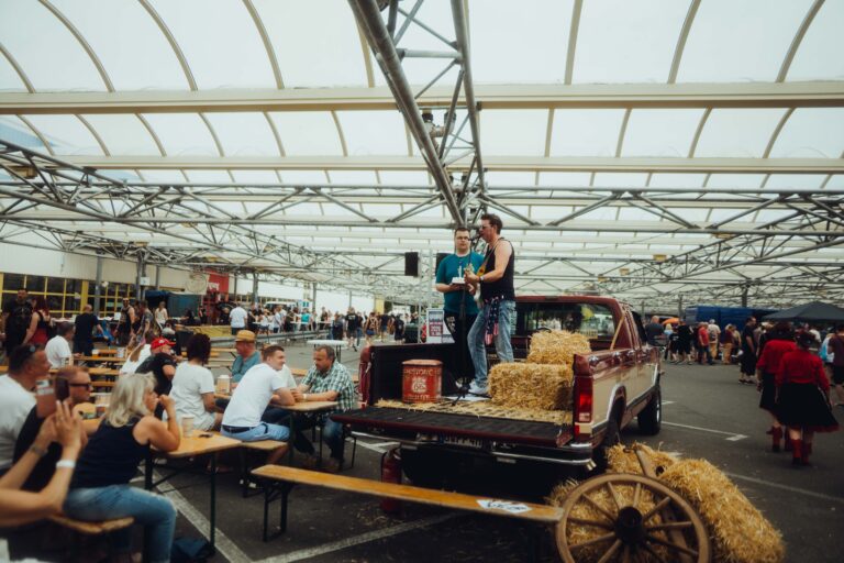 Biergarnituren und ein Pick-up mit Strohballen unter dem Hallendach