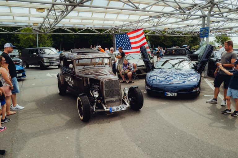 Schwarzer Hot Rod mit offenem Motor, dahinter eine US-Flagge