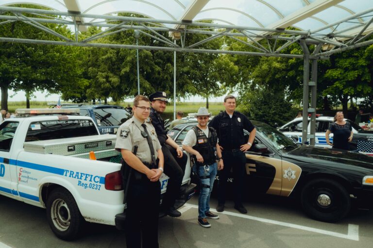 Pick-up im Polizei-Look, davor Besucher in Sheriff-Uniform